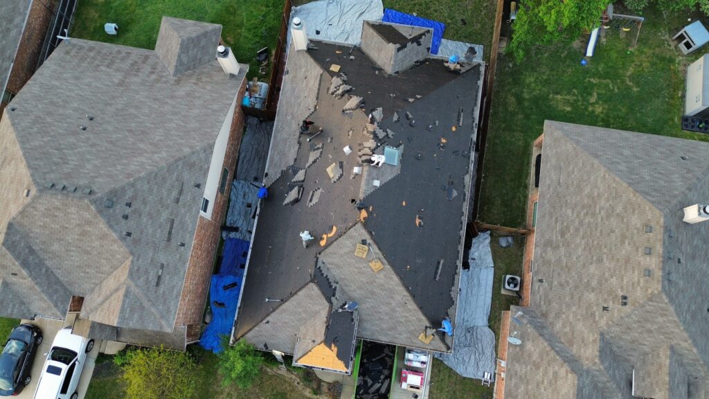 Aerial view of a residential roof undergoing repair in the Dallas-Fort Worth Metroplex, showcasing Roofing