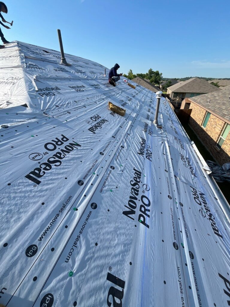 Roofers installing synthetic underlayment during a complete roof replacement project in Dallas-Fort Worth.