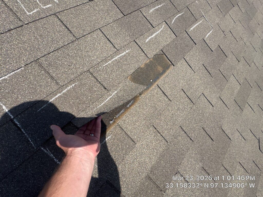 Roofing Redefined technician inspecting damaged asphalt shingles during a roof inspection in Dallas-Fort Worth.