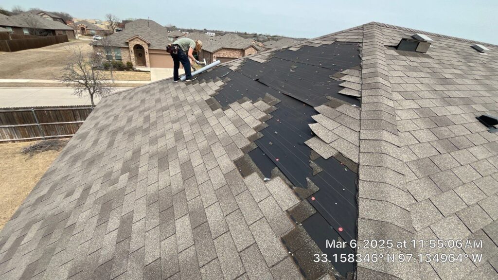Roofing Redefined technician inspecting and repairing damaged shingles on a residential roof in the Dallas-Fort