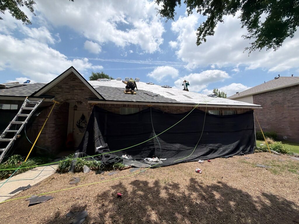 Roofers performing a complete roof replacement on a Dallas-Fort Worth home.