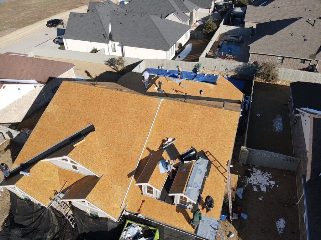 Aerial view of roofing contractors performing a complete residential roof replacement in Dallas-Fort Worth.