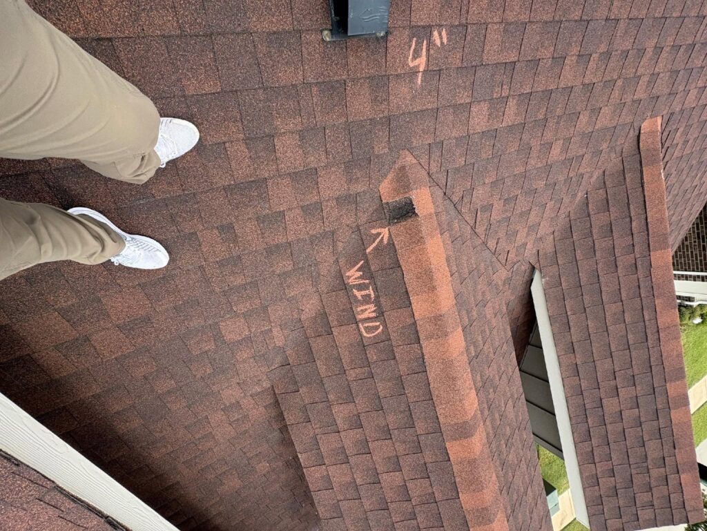 Roof inspector conducting a detailed roof damage assessment on a residential shingle roof in Dallas-Fort